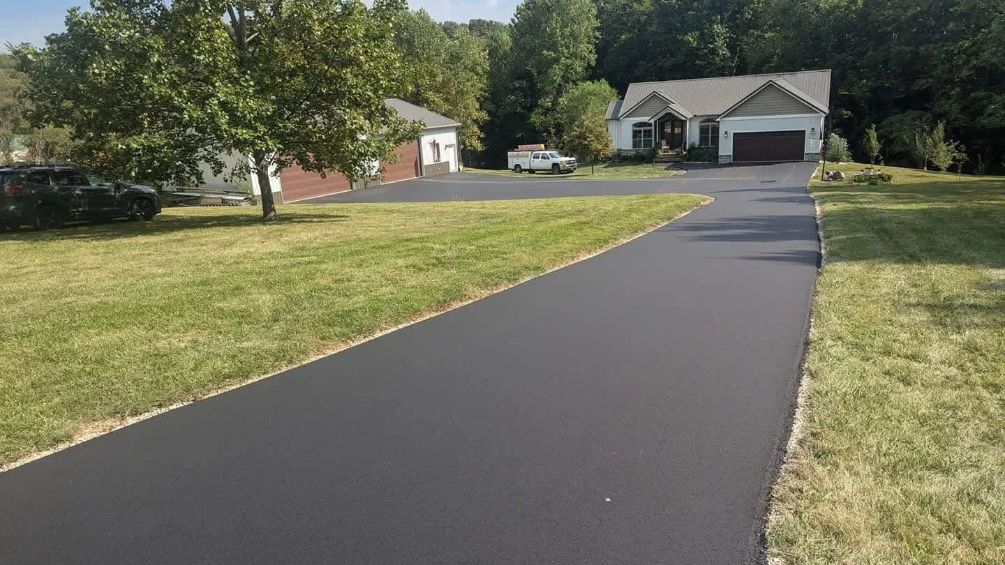 New asphalt driveway running up to a home with a detached garage, asphalt paving