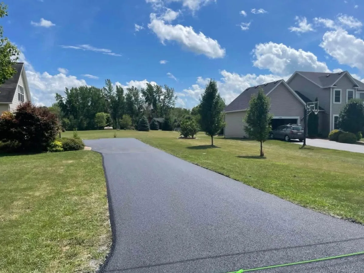 Freshly paved asphalt driveway running across a lawn between two homes, asphalt driveway paving