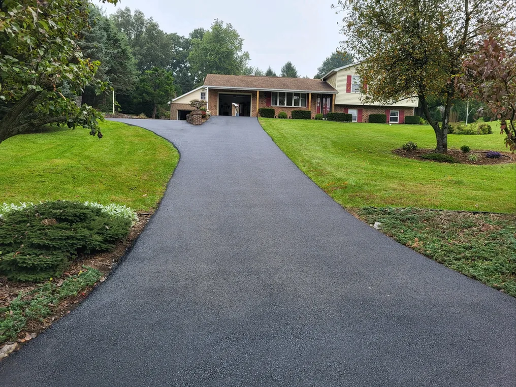 Freshly resurfaced asphalt driveway running up to a brick split level house, asphalt resurfacing