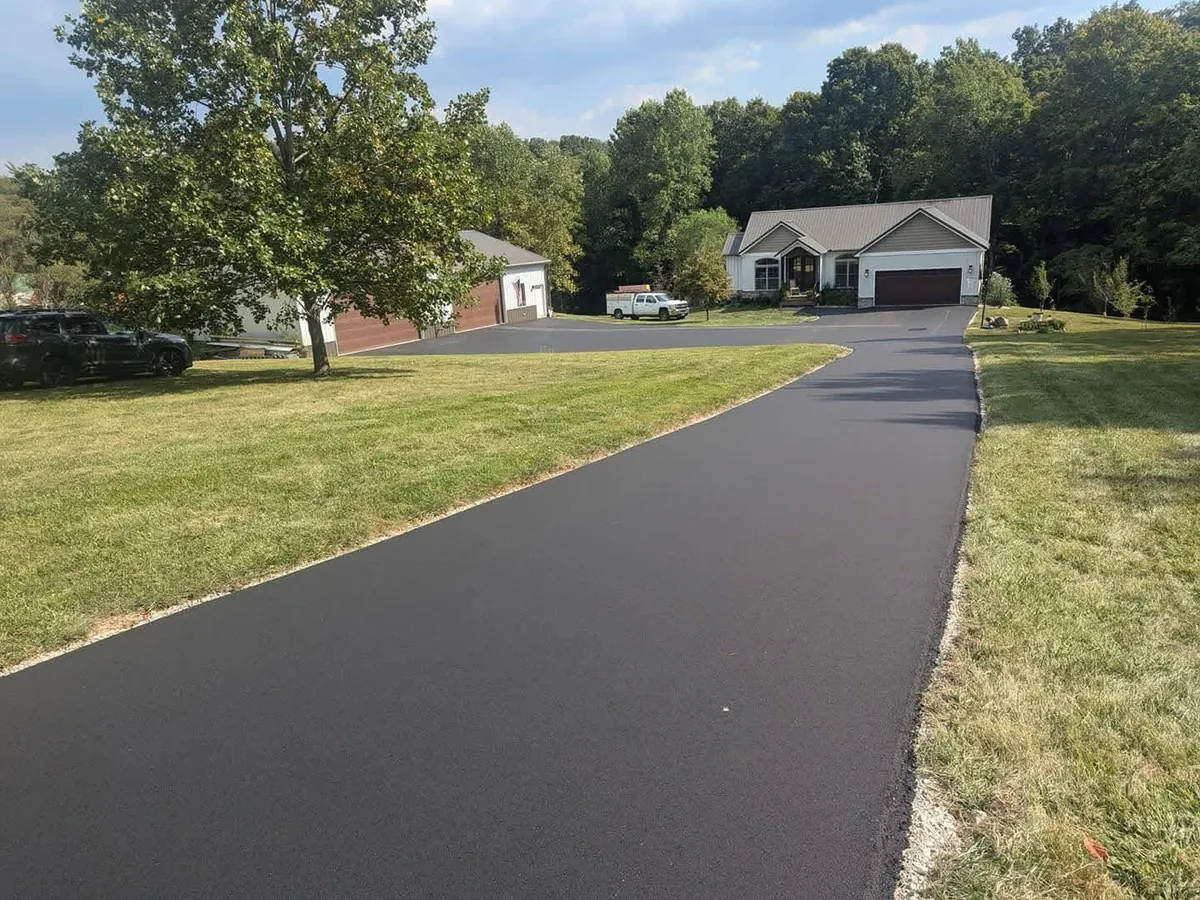 Long asphalt drive running past a lawn to a home and outbuildings, private road paving